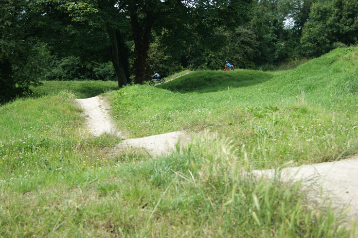 Two children on bikes riding on a BMX track.